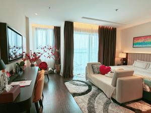 a bedroom with a bed and a desk and a couch at Sapphire Residence Hạ Long in Ha Long