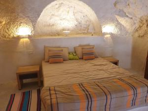 a bedroom with a bed in a stone wall at Dar Zmen Toujane in Tūjān