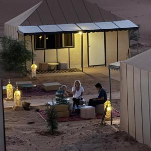 a group of people sitting under a tent at night at Camel Trekking Camp & Activities in Merzouga