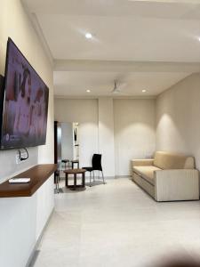 a living room with a couch and a tv on a wall at SeaYou Stay in Daman +12 photos