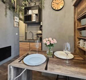 a table with plates and glasses and a clock on the wall at Petit nid douillet, à deux pas des commodités in Neuilly-Plaisance