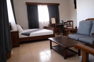 a living room with a bed and a couch and a table at RAOOF HOTEL in Mahajanga