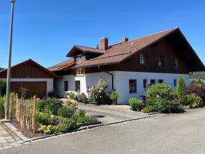 a large white house with a wooden roof at Ferienwohnung Sonnenblick in Grafenwiesen