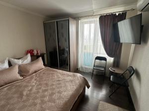 a bedroom with a bed and a desk and a window at Apartment in Zolotonosha