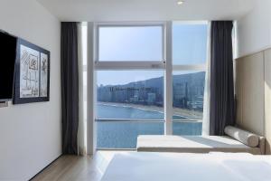 a bedroom with a large window with a view at Gwanganri HOTEL OCEANVIEW in Busan