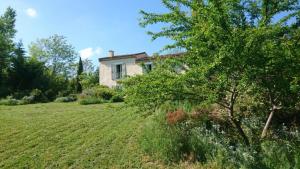 a house in a field with a tree in the foreground at Le Jardin d'Anna in Saint-Eutrope-de-Born +25 photos