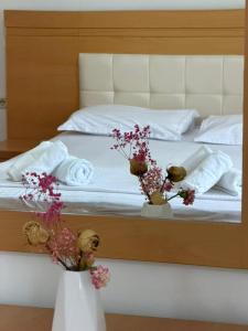 a bed with two vases with flowers on it at Marl's Home in Berat