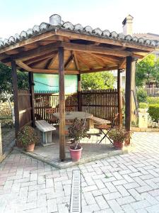 a wooden gazebo with a picnic table and a bench at Taku Rooms Vlora in Vlorë