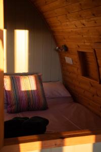 a bed in a wooden room with a pillow at Skylark - Pod in Northrepps
