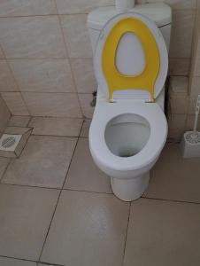 a bathroom with a toilet with a yellow seat at Greatwall golden stay in Machakos