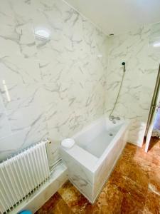 a bathroom with a white tub and marble walls at La Maison Bloom in Houilles +11 photos
