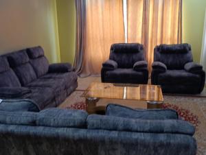 a living room with a couch and two chairs and a table at Greatwall golden stay in Machakos
