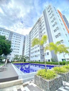 a large apartment building with a swimming pool and palm trees at Urban Oasis Symphony Pool in Cebu City