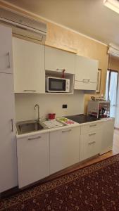 a kitchen with white cabinets and a sink and a microwave at Casa Vacanze Cesarina - Catanzaro centro in Catanzaro +5 photos