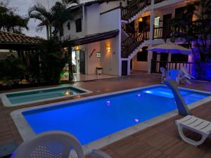 a house with a blue swimming pool at night at Pousada Stella Tropical in Salvador +19 photos