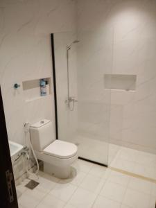 a white bathroom with a toilet and a shower at شقة واحة رتيل الفندقية in Al-ʿUla