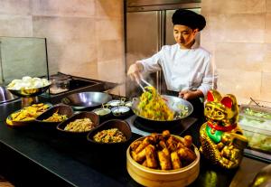 a woman preparing food in a kitchen with bowls of food at Barceló Teguise Beach - Adults Only in Costa Teguise