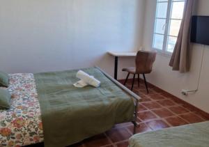 a bedroom with two beds and a desk and a chair at Hôtel restaurant ANGEL'S in Angles