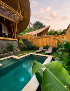 a swimming pool in a backyard with a wooden fence at Hidden Bamboo Village in Sidemen