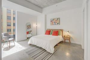 a white bedroom with a bed and a chair at Downtown Miami Condo with Balcony & Rooftop Pool in Miami