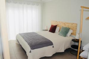 a bedroom with a large white bed with colorful pillows at Cantinho do Pópulo - Beach House in Ponta Delgada