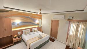 ein Schlafzimmer mit einem großen Bett und einem Gemälde an der Wand in der Unterkunft Hotel Simha Skylight - Tirupati in Tirupati