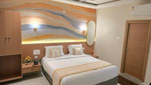 ein Hotelzimmer mit einem Bett und einem Gemälde an der Wand in der Unterkunft Hotel Simha Skylight - Tirupati in Tirupati + 25 Fotos