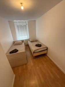 two beds in a small room with a window at Maison 3 chambres - Parking privé in Gandrange