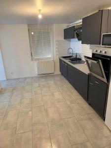 a kitchen with black cabinets and a tile floor at Maison 3 chambres - Parking privé in Gandrange