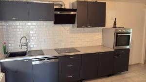 a kitchen with black cabinets and a sink and a microwave at Maison 3 chambres - Parking privé in Gandrange