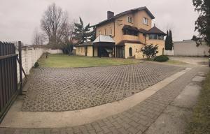 a house with a brick driveway in front of it at Hostel Arkobaleno sieci Mazowia Hostels Group in Marki