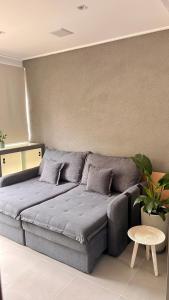 a gray bed in a room with a table at Apartamento Giardino Maia, Café da Manhã cortesia em dias úteis in Guarulhos
