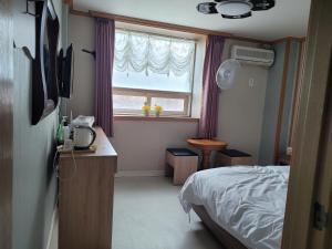 a bedroom with a bed and a window with purple curtains at 힐하우스 in Chŏngp'op'ogu