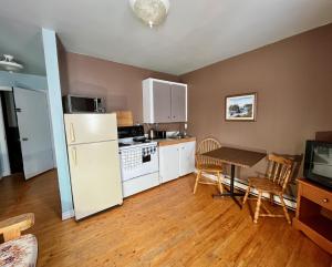 a kitchen with a white refrigerator and a table with chairs at Bennett Lodge in Daniels Harbour