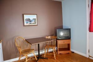 a dining room table with two chairs and a tv at Bennett Lodge in Daniels Harbour