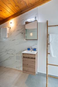 a bathroom with a sink and a marble wall at MyPanormo Suites - Philip in Panormos Rethymno +13 photos