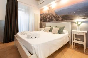 a bedroom with a large white bed with a painting on the wall at Heart of Pescara Elegant Suites - Chic Suites in Pescara Center & 2 steps from Sea - AC & Wifi in Pescara