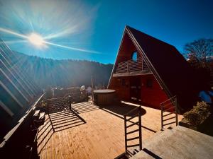 a building with a deck with benches and the sun at Twin Cabins Azuga in Azuga