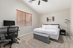 a bedroom with a bed and a desk with a computer at Pet-Friendly 4BR Oasis - Heated Pool Firepit & BBQ in Chandler