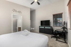 a bedroom with a bed and a desk and a tv at Pet-Friendly 4BR Oasis - Heated Pool Firepit & BBQ in Chandler +36 photos