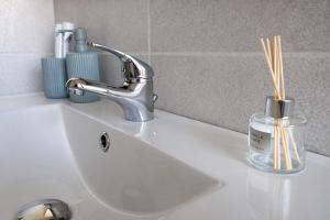 a sink with a faucet and bamboo sticks in a glass jar at LaBohème Lake Maggiore Retreat with Private Beach in Dormelletto +13 photos
