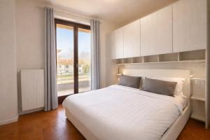 a bedroom with a white bed and a large window at LaBohème Lake Maggiore Retreat with Private Beach in Dormelletto