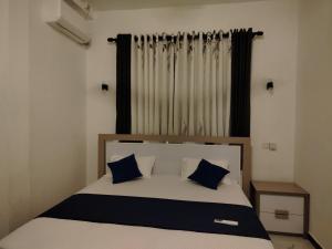 a bedroom with a bed with blue pillows and a window at Stay Roside Villa Hikkaduwa in Hikkaduwa