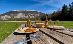 a table with two plates of food and two bottles of beer at Glamping at Camping La Source in Saint-Pierre-dʼArgençon