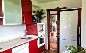 a kitchen with red cabinets and a white refrigerator at Villa Galana Oyambre in Los Llaós