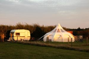 a white tent and a trailer in a field at Stargazer Bell Tent in Northrepps