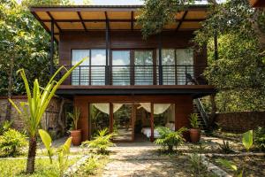 a wooden house with glass doors and trees at Hidden Paradise West Sumbawa Yo Yos in Sekongkang Bawa