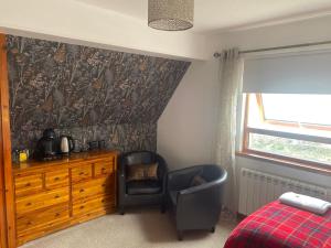 a bedroom with a chair and a dresser and a bed at Lochview Guest House in Ullapool