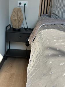 ein Schlafzimmer mit einem Bett und einem Nachttisch mit einer Lampe in der Unterkunft Voogdtstraat 7 in Sluis