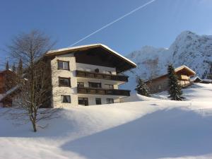ein Gebäude im Schnee vor einem Berg in der Unterkunft Im Höfle Ferienwohnungen in Mittelberg